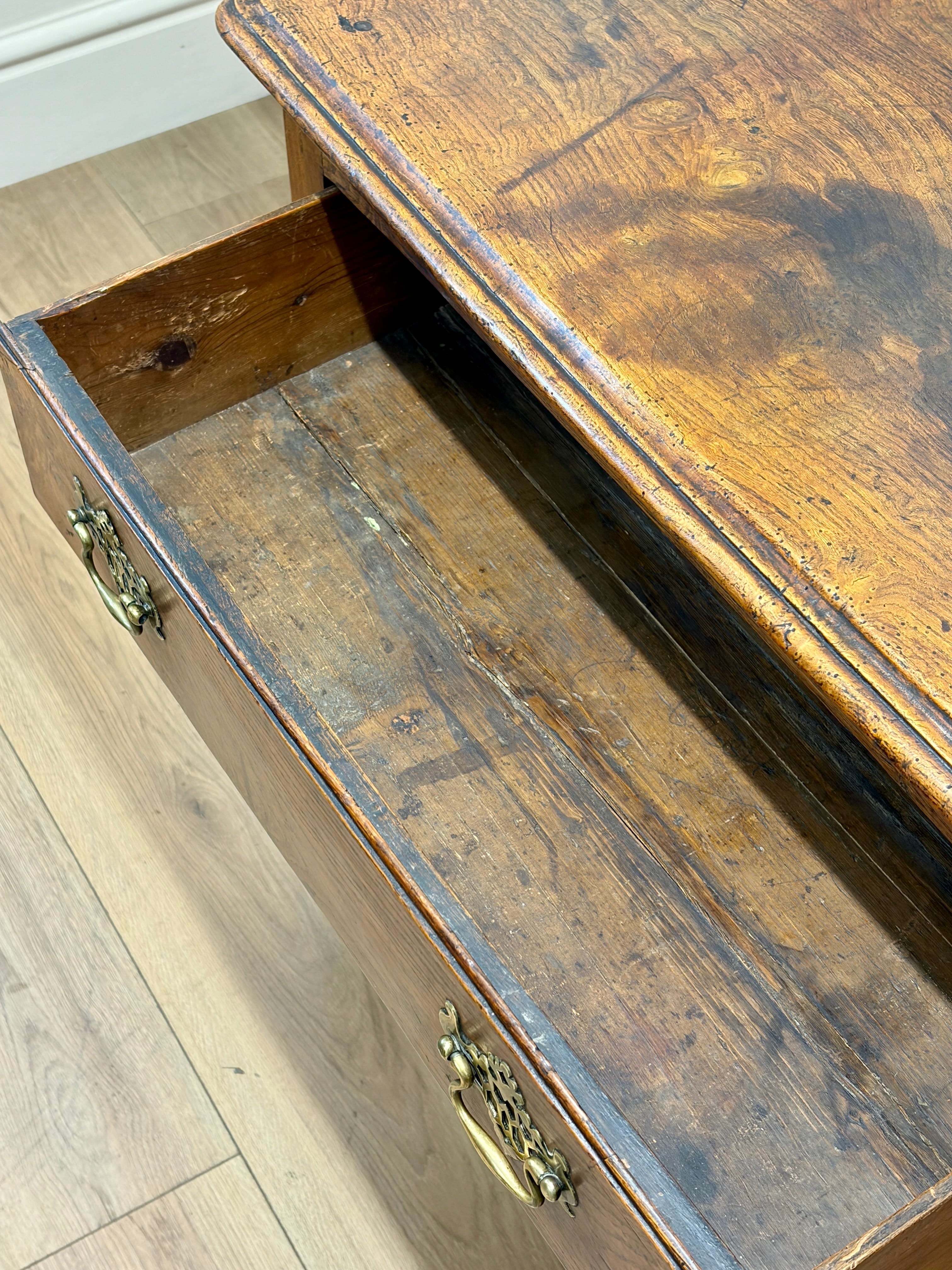 Wooden drawer with brass handles on a wooden floor.