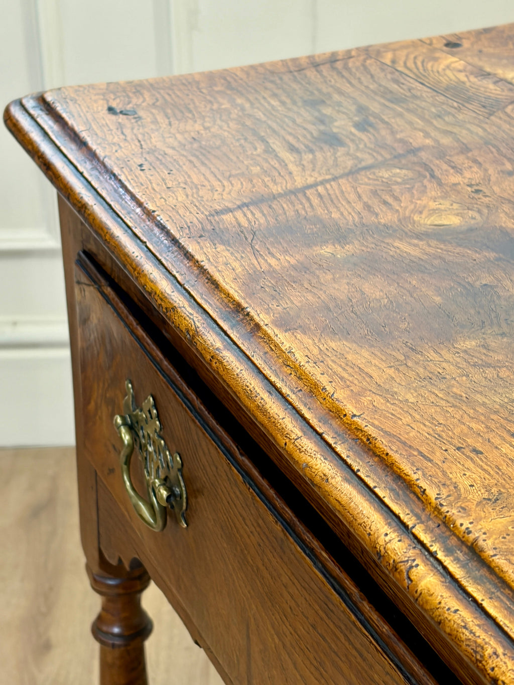 Close-up of a wooden desk with a brass handle.