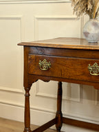Wooden side table with brass handles against a beige wall