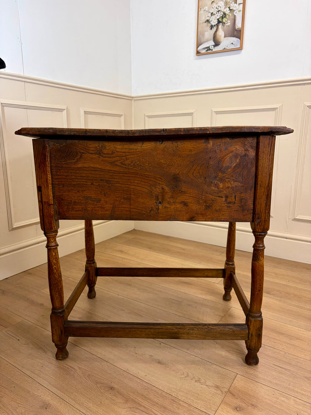 Wooden table in a room with white walls and wooden floor.