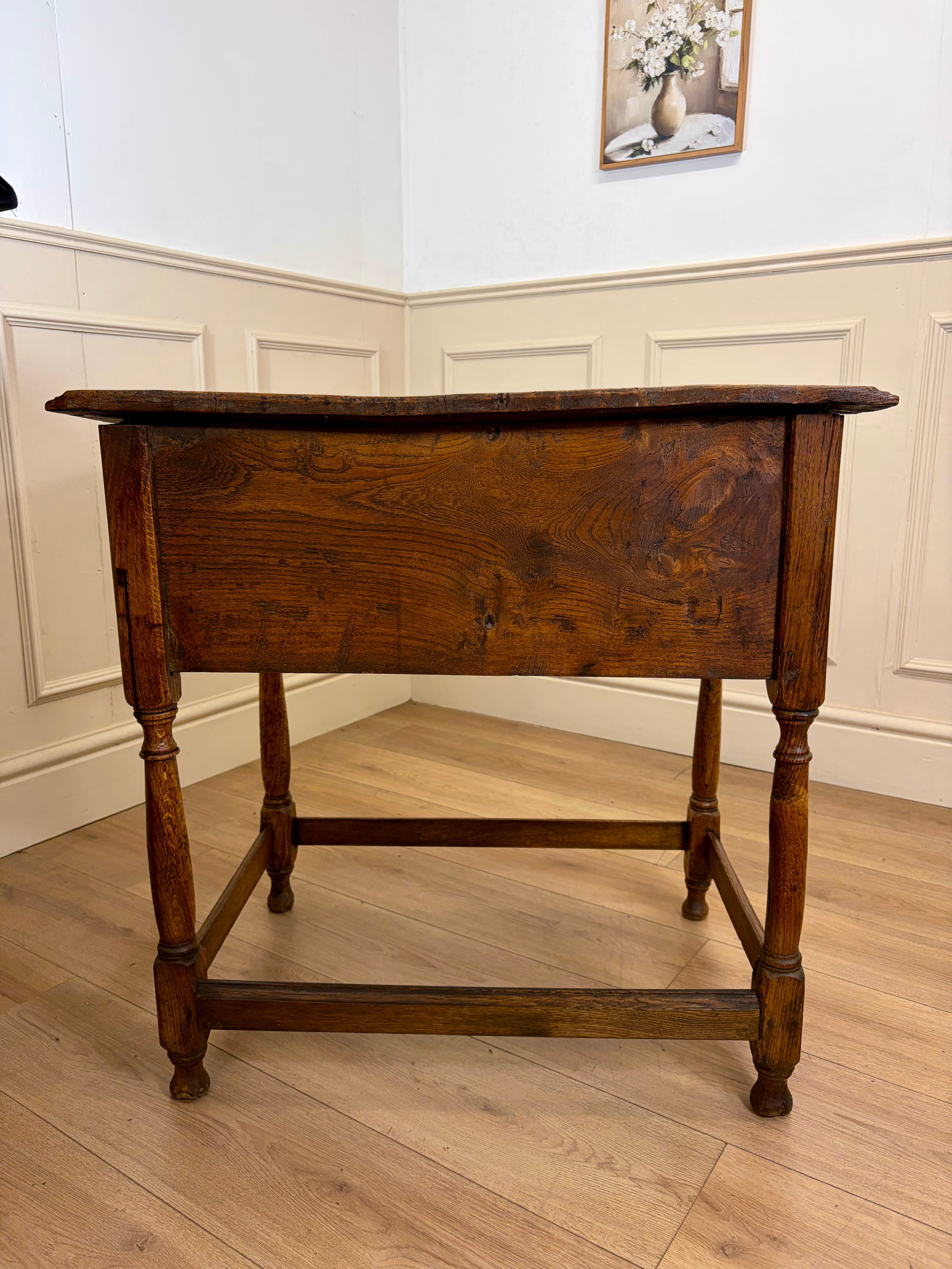 Wooden table in a room with white walls and wooden floor.