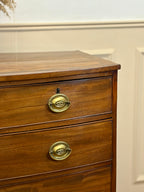 Wooden dresser with brass handles on a white wall background