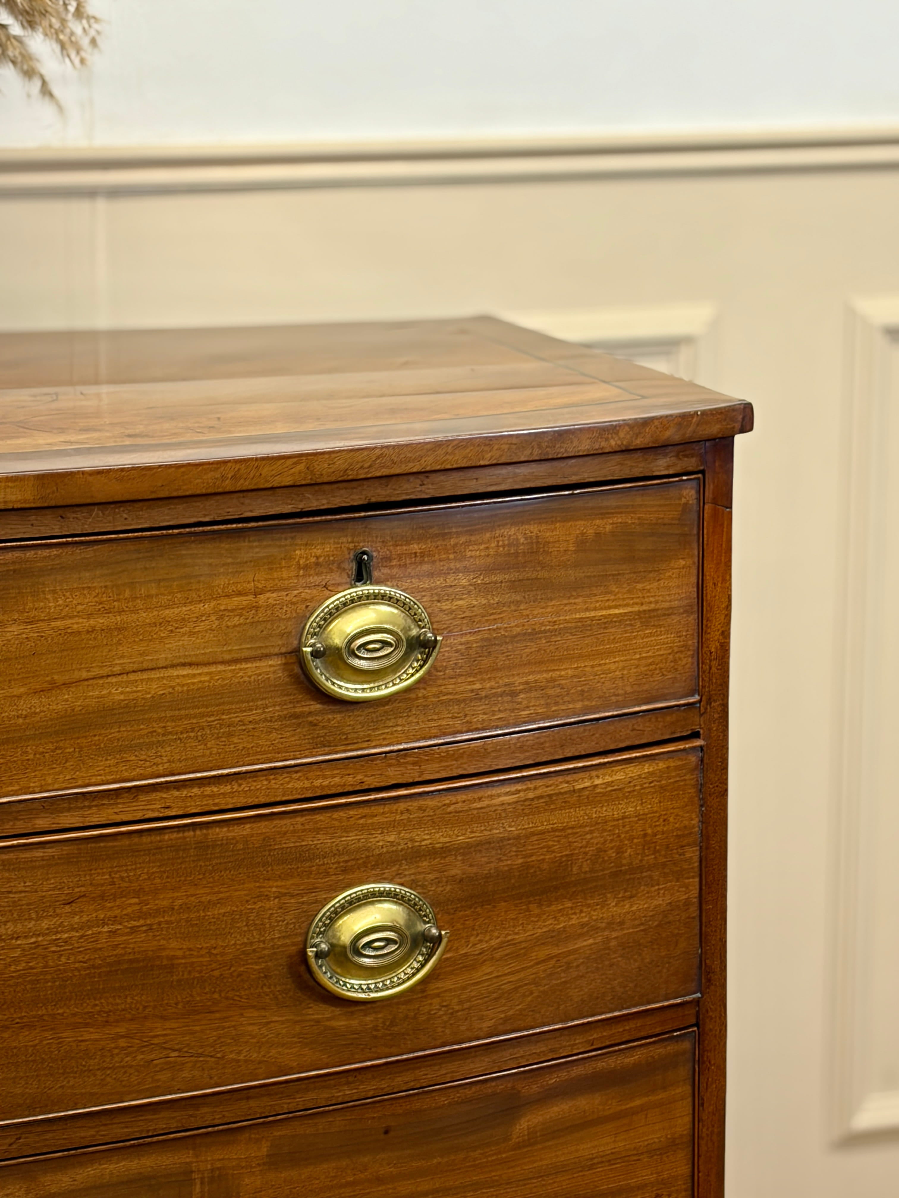 Wooden dresser with brass handles on a white wall background