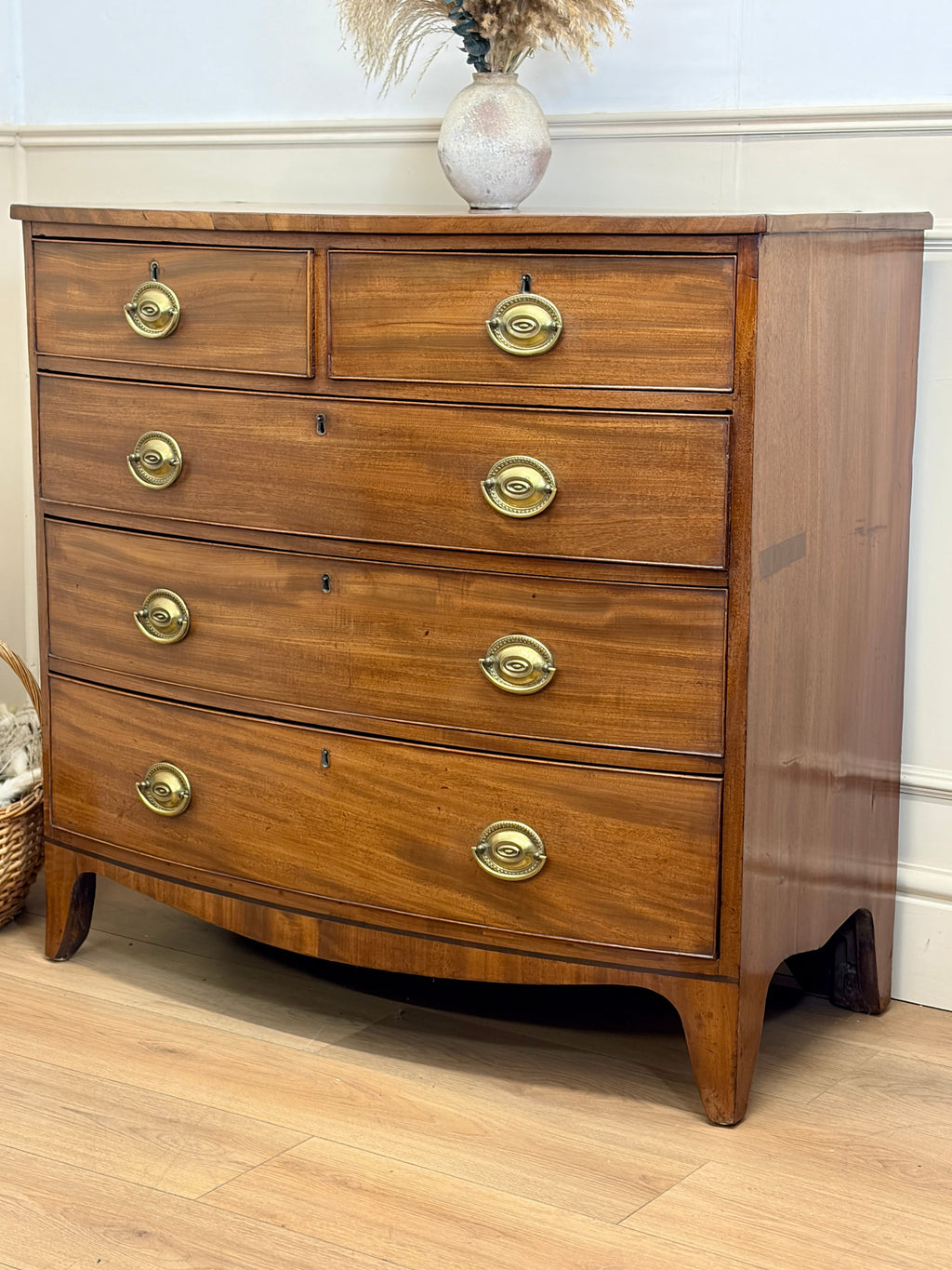 Wooden dresser with brass handles on a wooden floor.