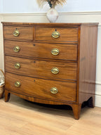 Wooden dresser with brass handles on a wooden floor.