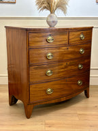 Wooden dresser with brass handles on a wooden floor.