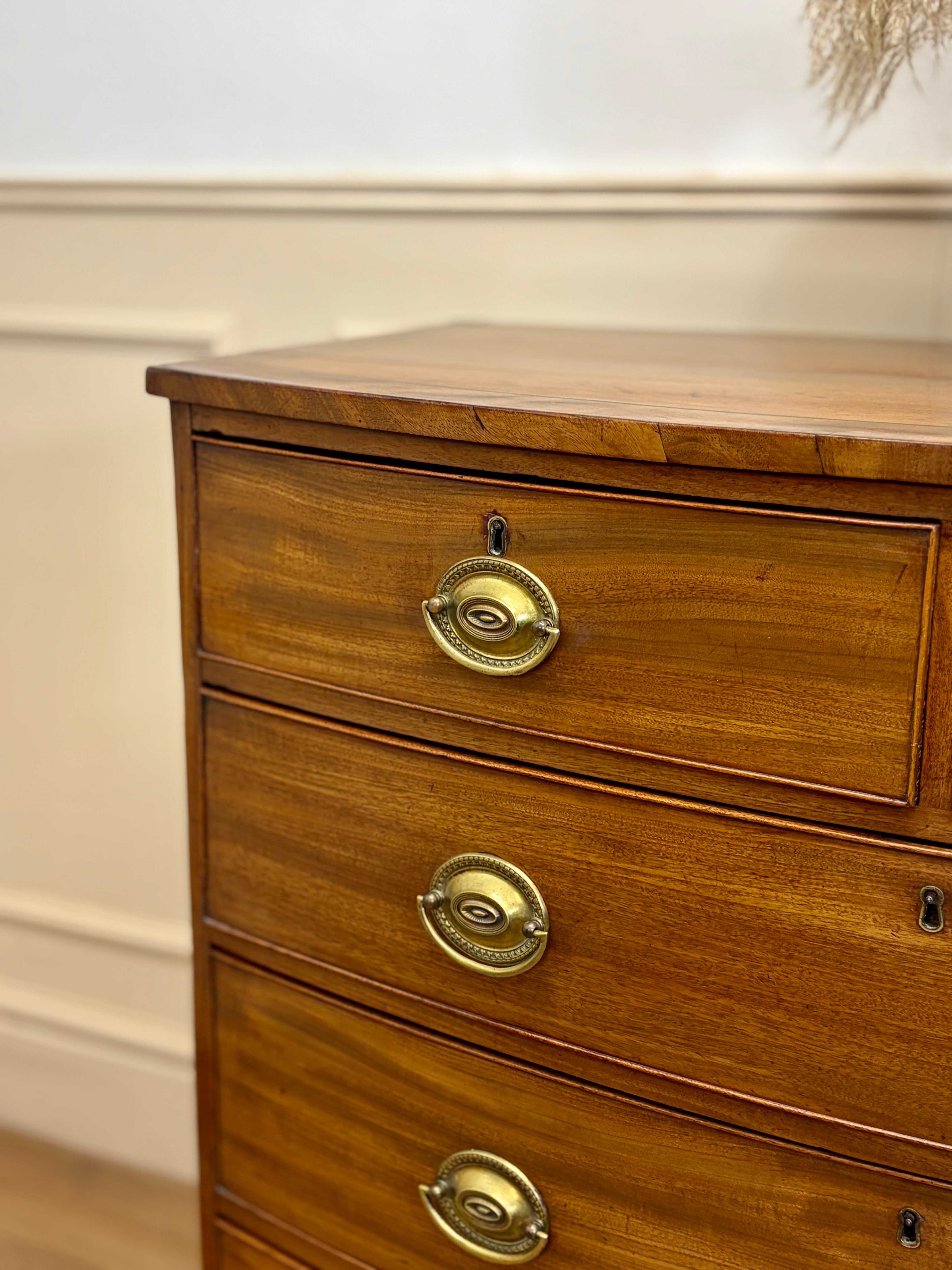 Wooden dresser with brass handles against a neutral wall.