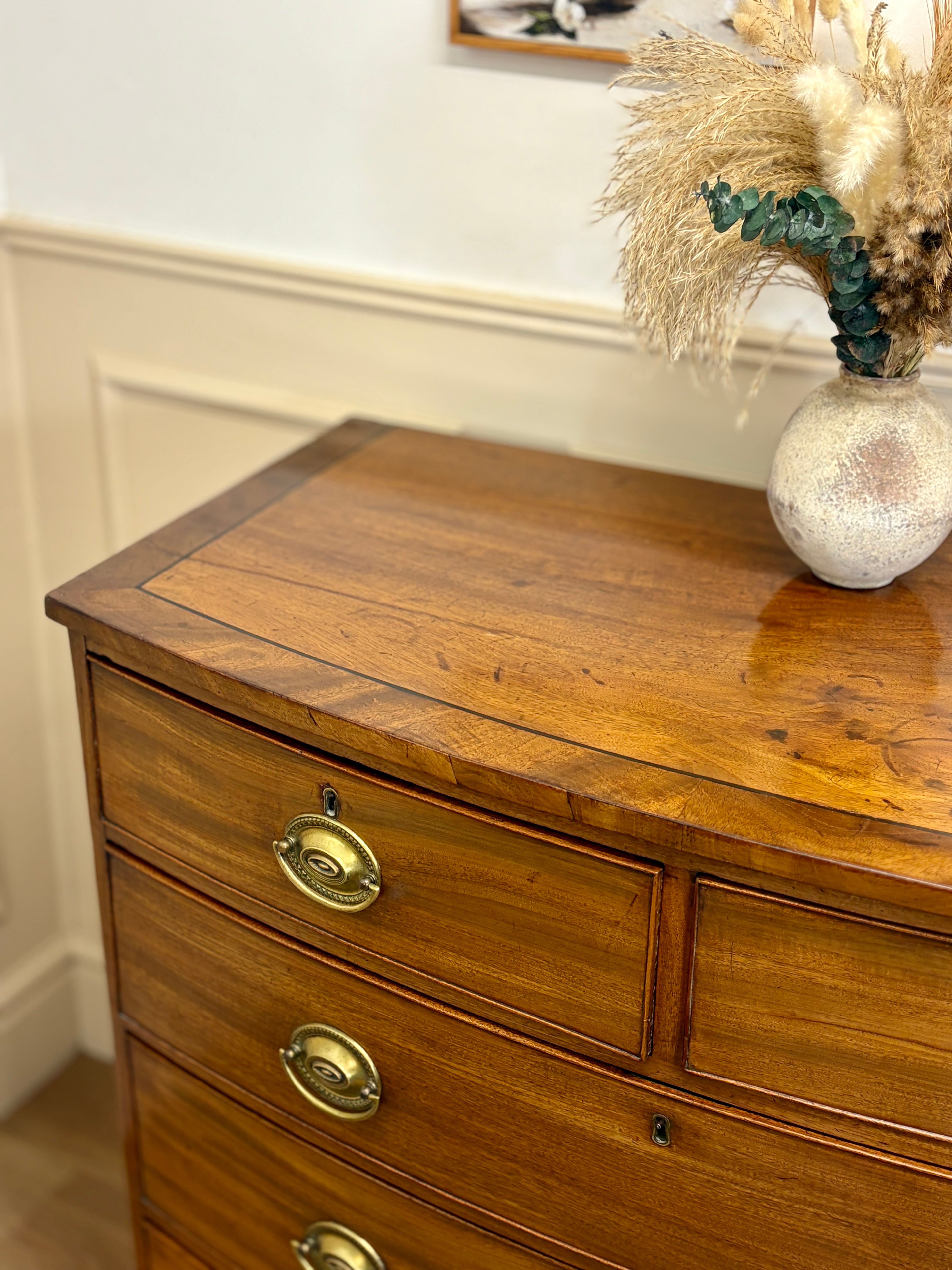 Wooden dresser with brass handles on a white wall background