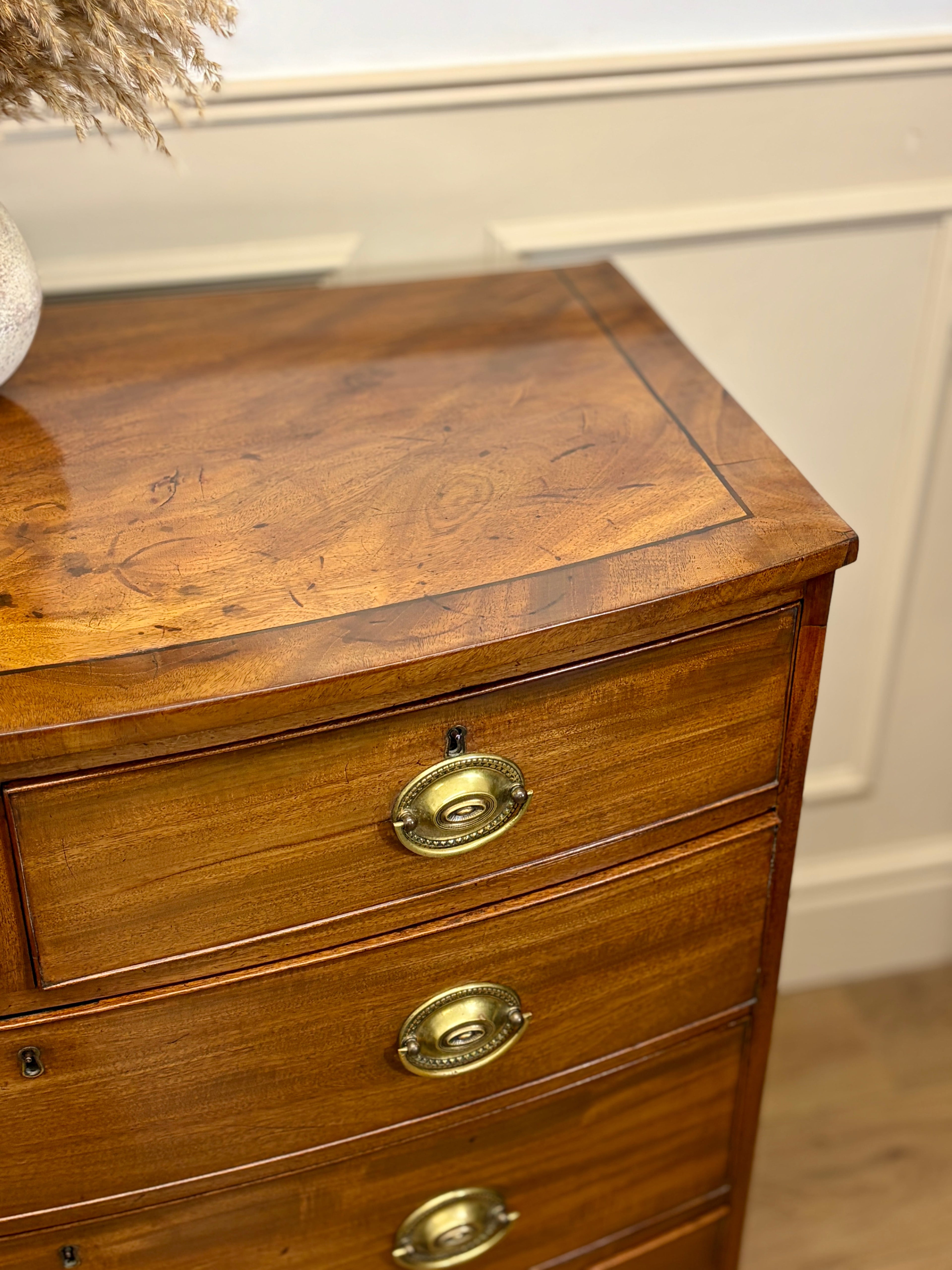 Wooden dresser with brass handles against a neutral wall.