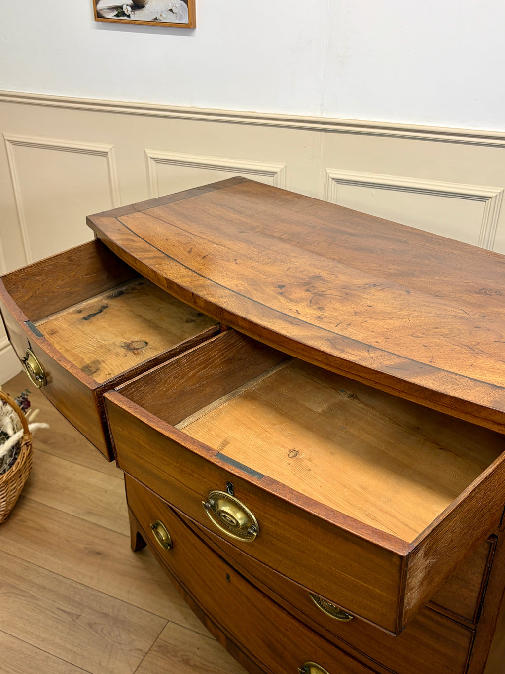 Wooden dresser with open drawers in a room with white walls and wooden floor.
