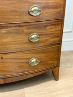 Wooden dresser with brass handles on a light wooden floor.