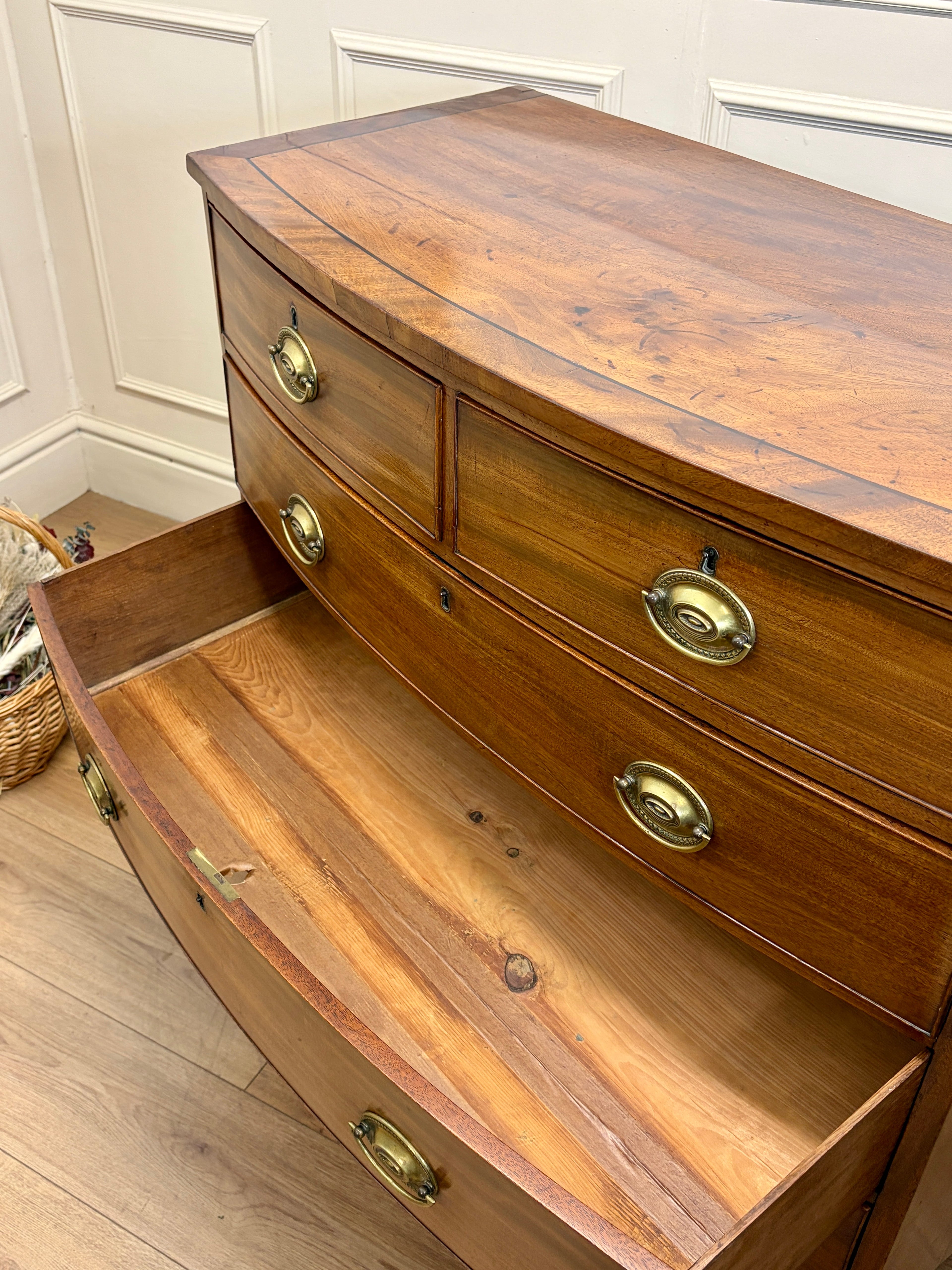 Wooden dresser with brass handles in a room with white paneled walls.