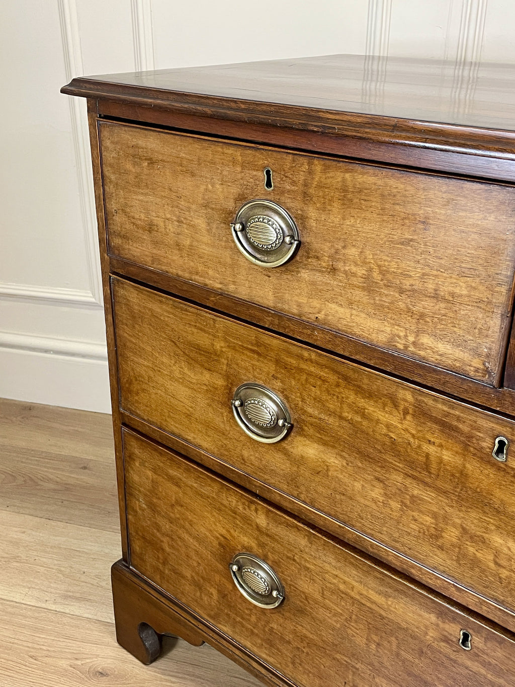 Angled view of late 19th century mahogany farmhouse chest of drawers with shaped bracket feet and elegant country furniture styling.