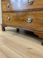 Angled view of late 19th century mahogany farmhouse chest of drawers with shaped bracket feet and elegant country furniture styling.