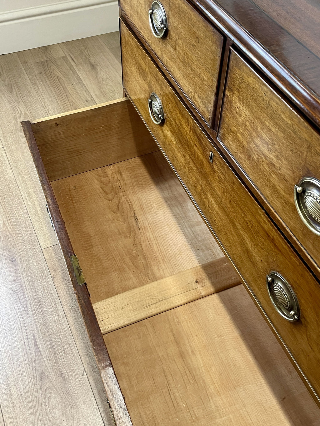 Angled view of late 19th century mahogany farmhouse chest of drawers with shaped bracket feet and elegant country furniture styling.
