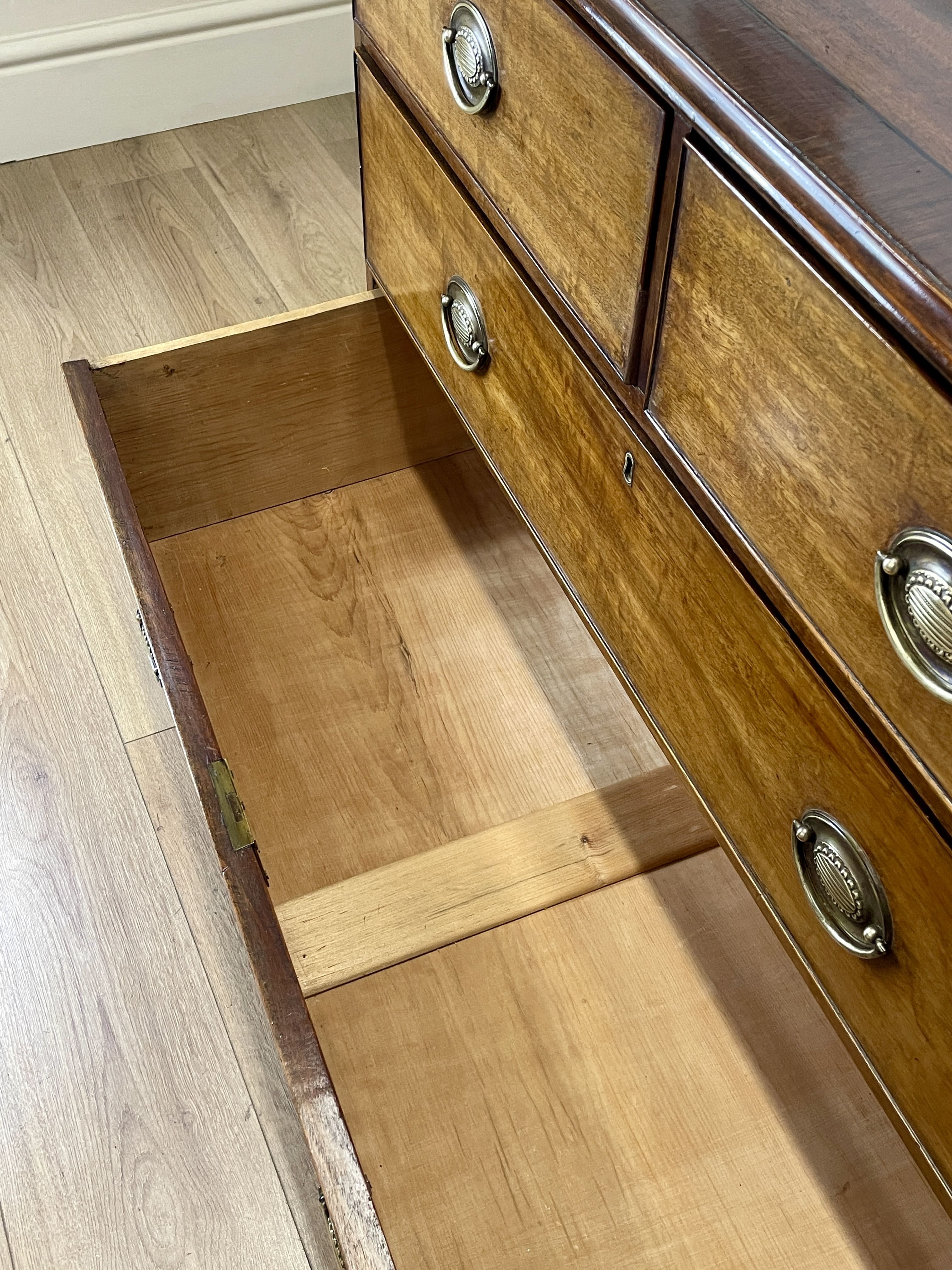 Angled view of late 19th century mahogany farmhouse chest of drawers with shaped bracket feet and elegant country furniture styling.