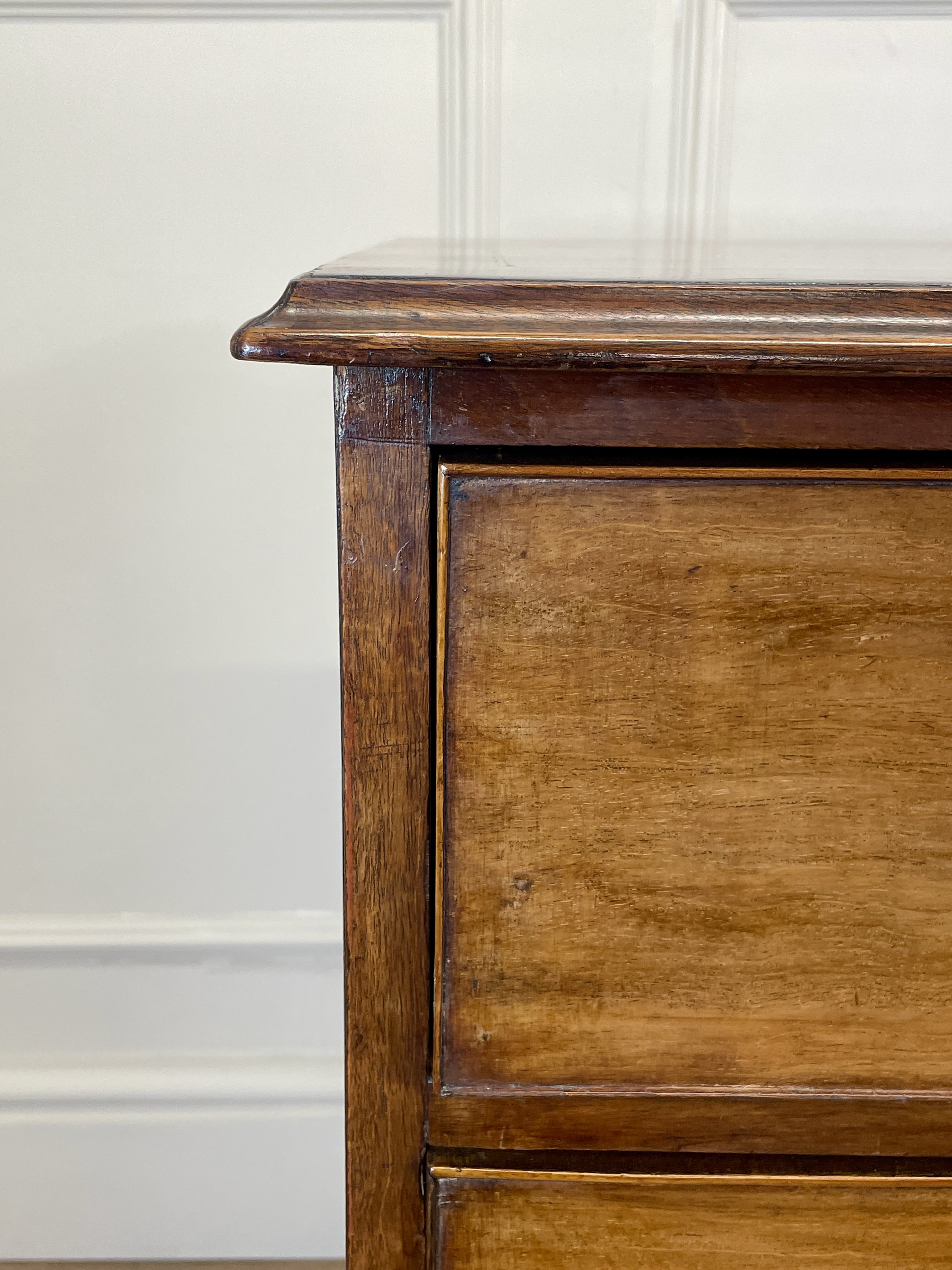 Angled view of late 19th century mahogany farmhouse chest of drawers with shaped bracket feet and elegant country furniture styling.