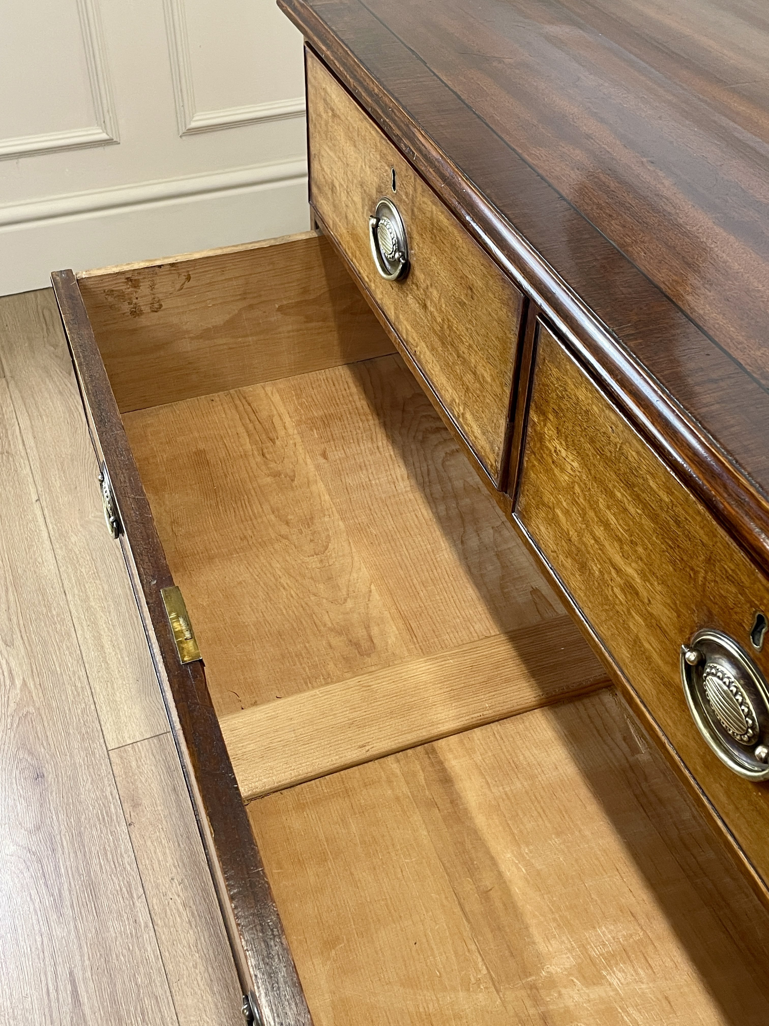 Angled view of late 19th century mahogany farmhouse chest of drawers with shaped bracket feet and elegant country furniture styling.