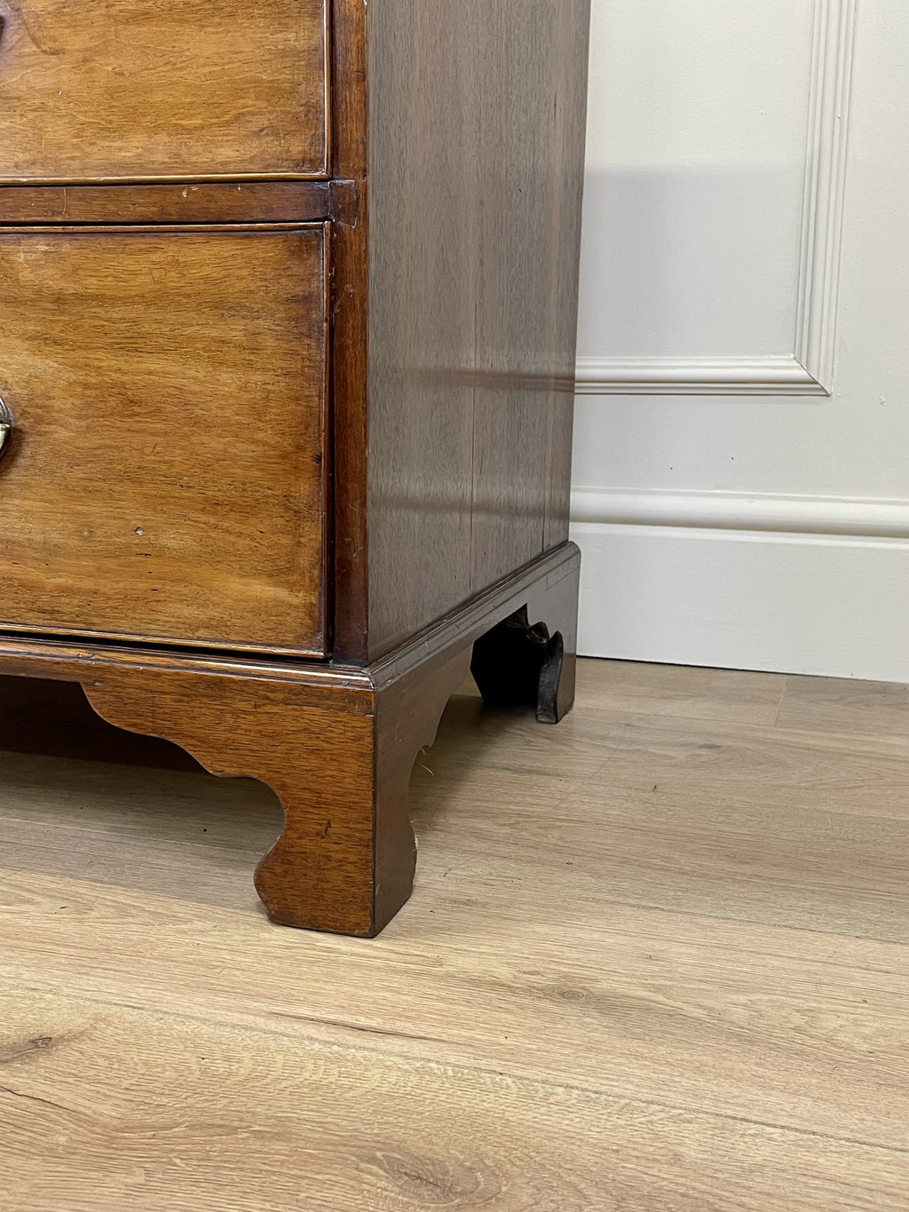 Angled view of late 19th century mahogany farmhouse chest of drawers with shaped bracket feet and elegant country furniture styling.