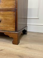 Angled view of late 19th century mahogany farmhouse chest of drawers with shaped bracket feet and elegant country furniture styling.