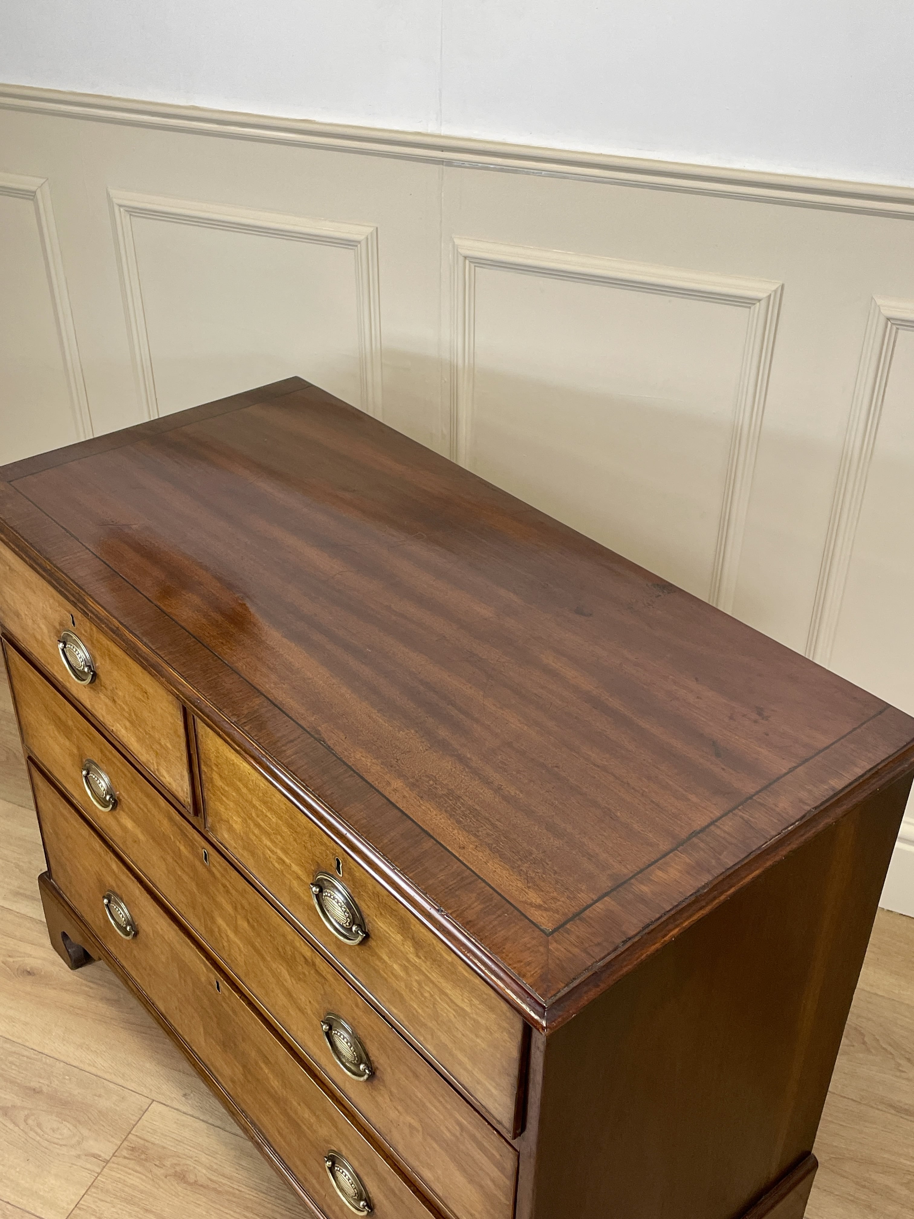 Angled view of late 19th century mahogany farmhouse chest of drawers with shaped bracket feet and elegant country furniture styling.