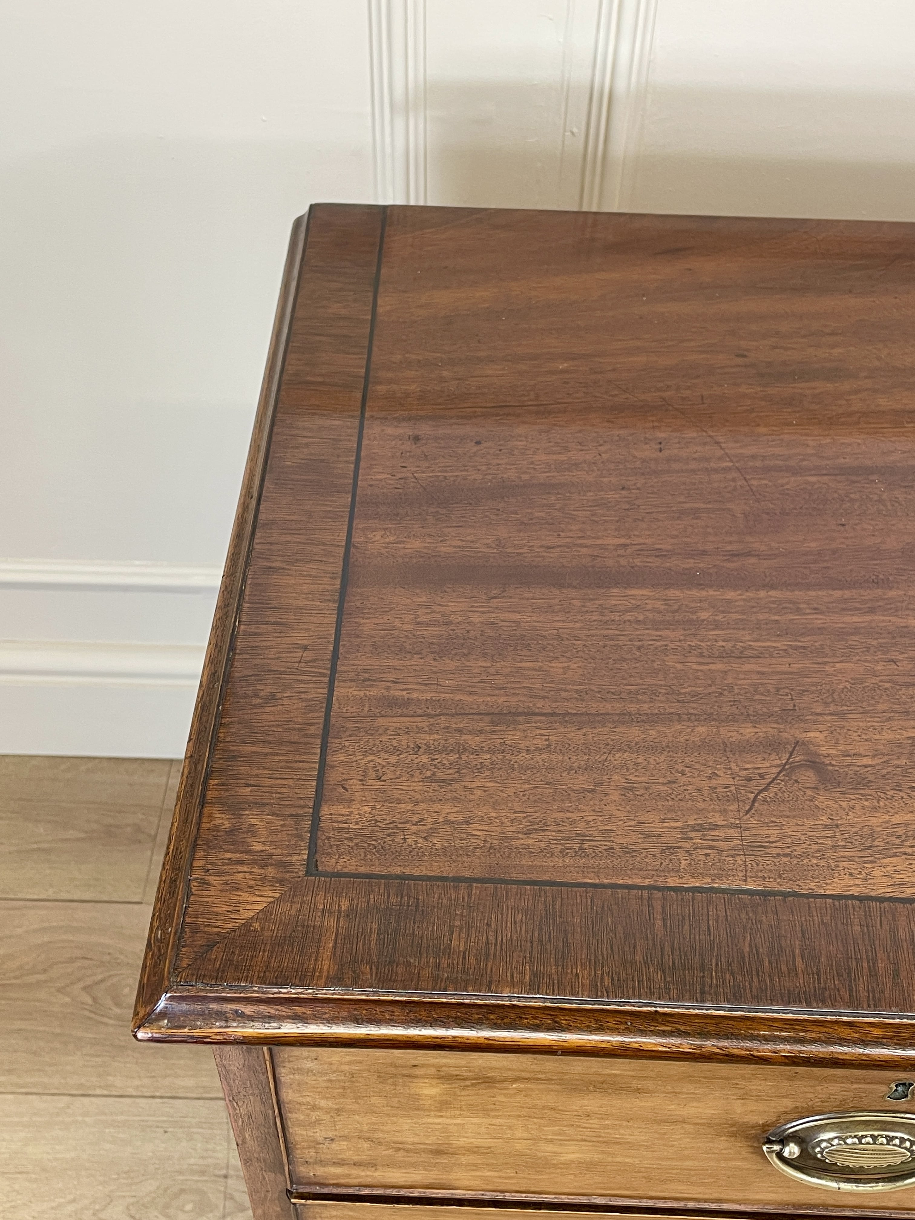Angled view of late 19th century mahogany farmhouse chest of drawers with shaped bracket feet and elegant country furniture styling.