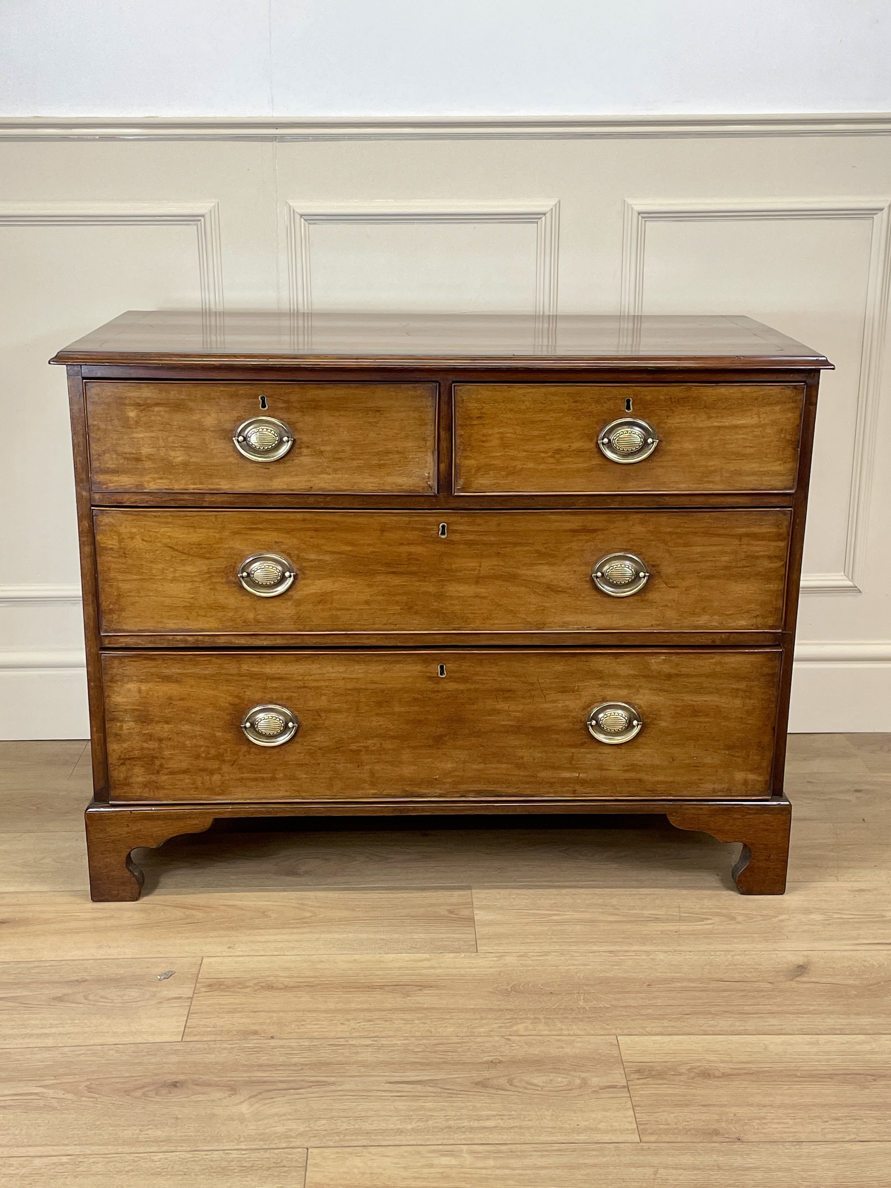 Angled view of late 19th century mahogany farmhouse chest of drawers with shaped bracket feet and elegant country furniture styling.
