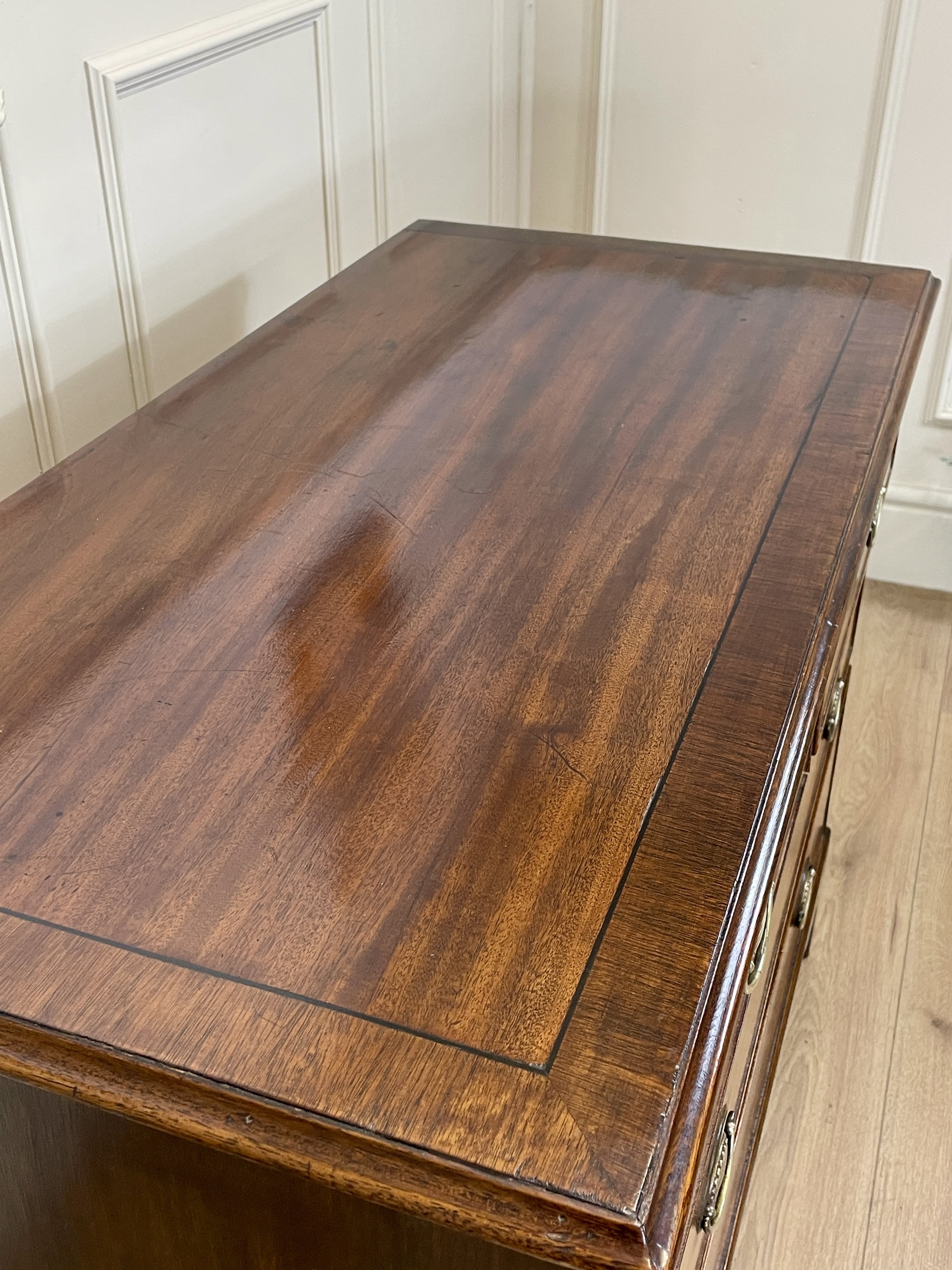 Angled view of late 19th century mahogany farmhouse chest of drawers with shaped bracket feet and elegant country furniture styling.