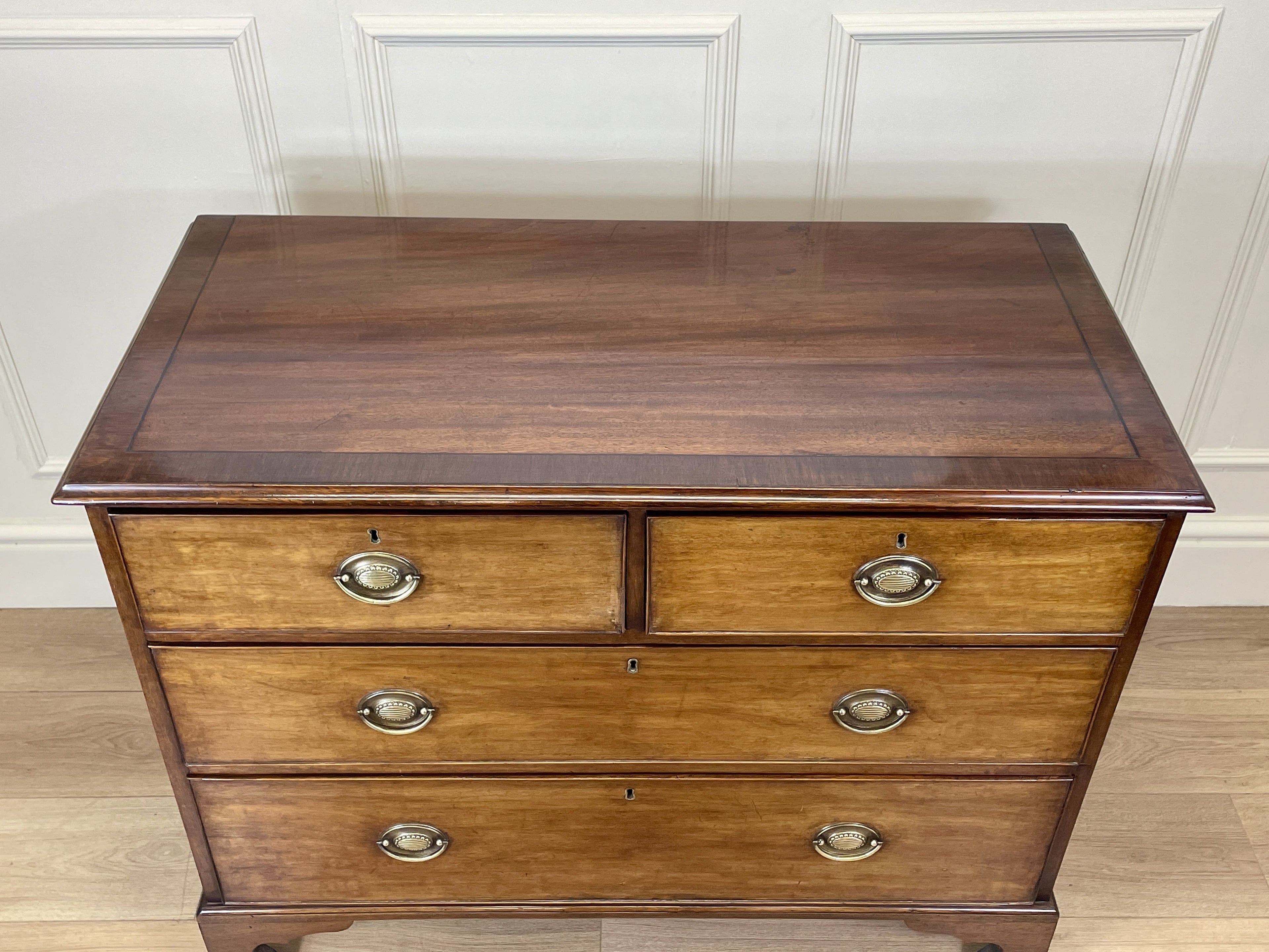 Angled view of late 19th century mahogany farmhouse chest of drawers with shaped bracket feet and elegant country furniture styling.