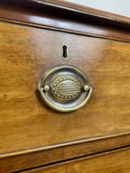 Angled view of late 19th century mahogany farmhouse chest of drawers with shaped bracket feet and elegant country furniture styling.
