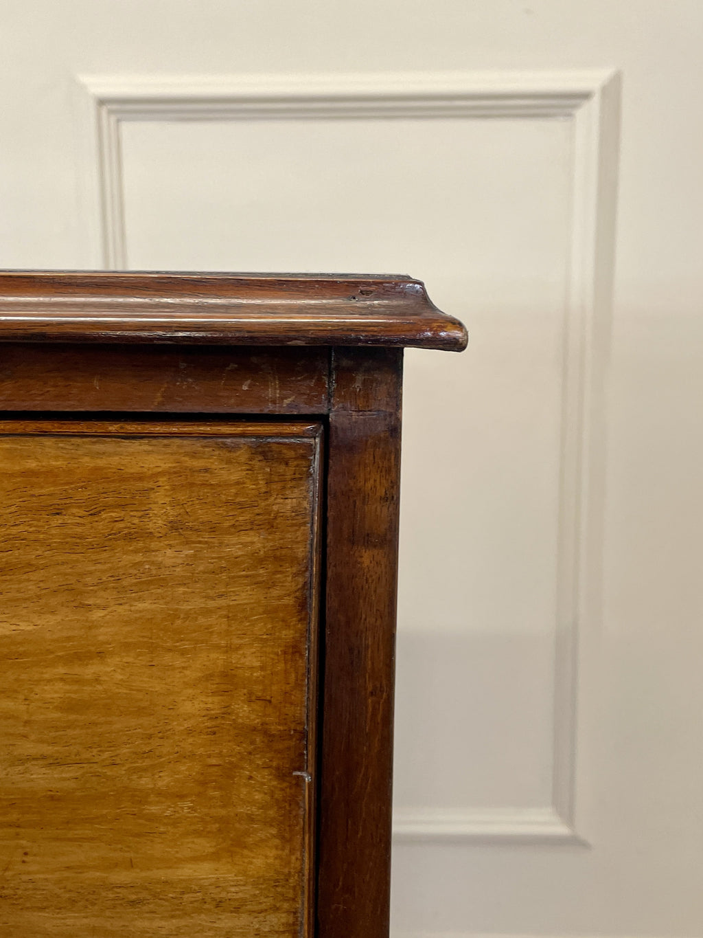 Angled view of late 19th century mahogany farmhouse chest of drawers with shaped bracket feet and elegant country furniture styling.