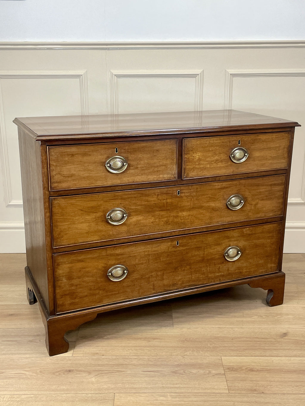 Angled view of late 19th century mahogany farmhouse chest of drawers with shaped bracket feet and elegant country furniture styling.