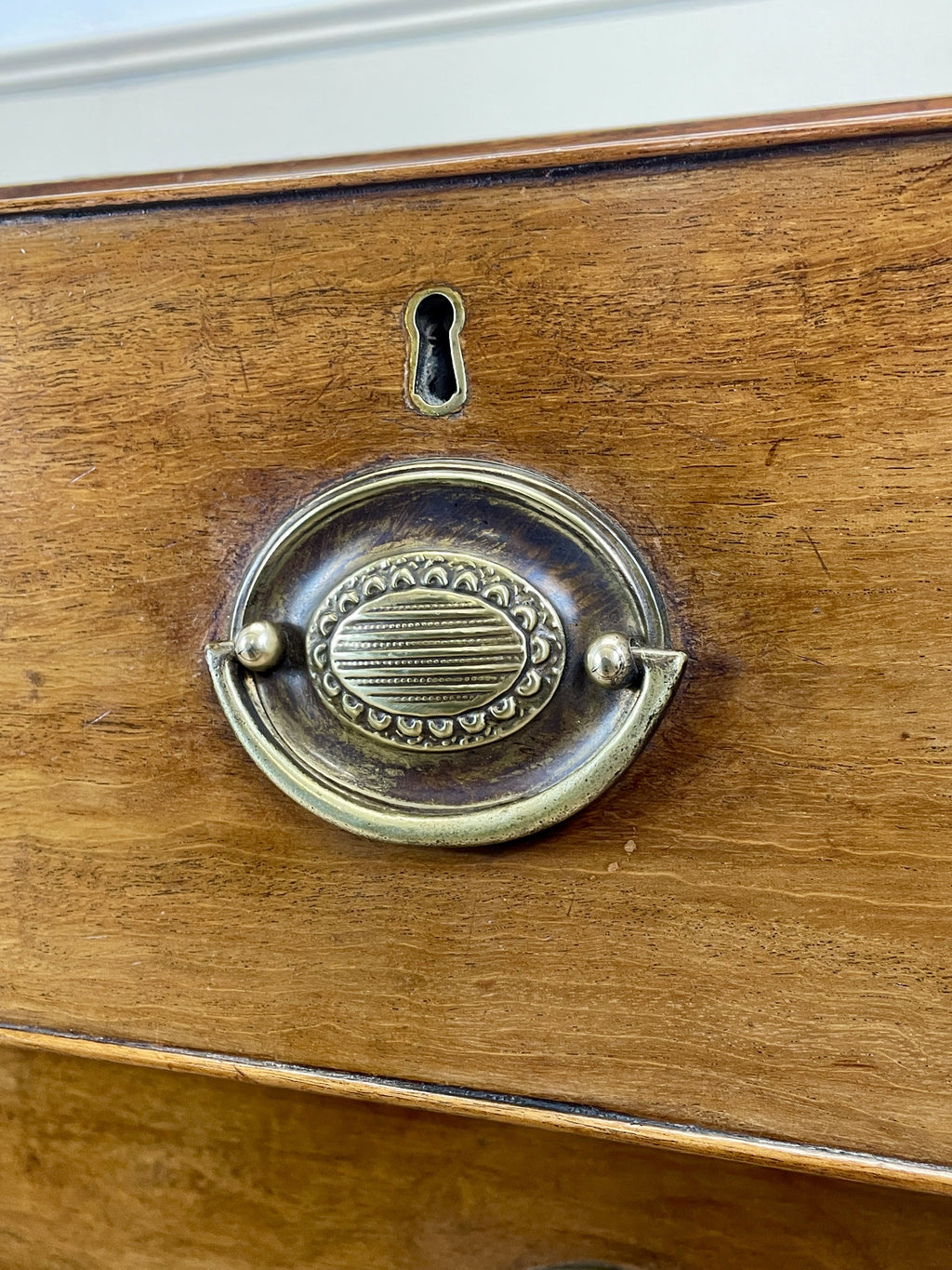 Angled view of late 19th century mahogany farmhouse chest of drawers with shaped bracket feet and elegant country furniture styling.