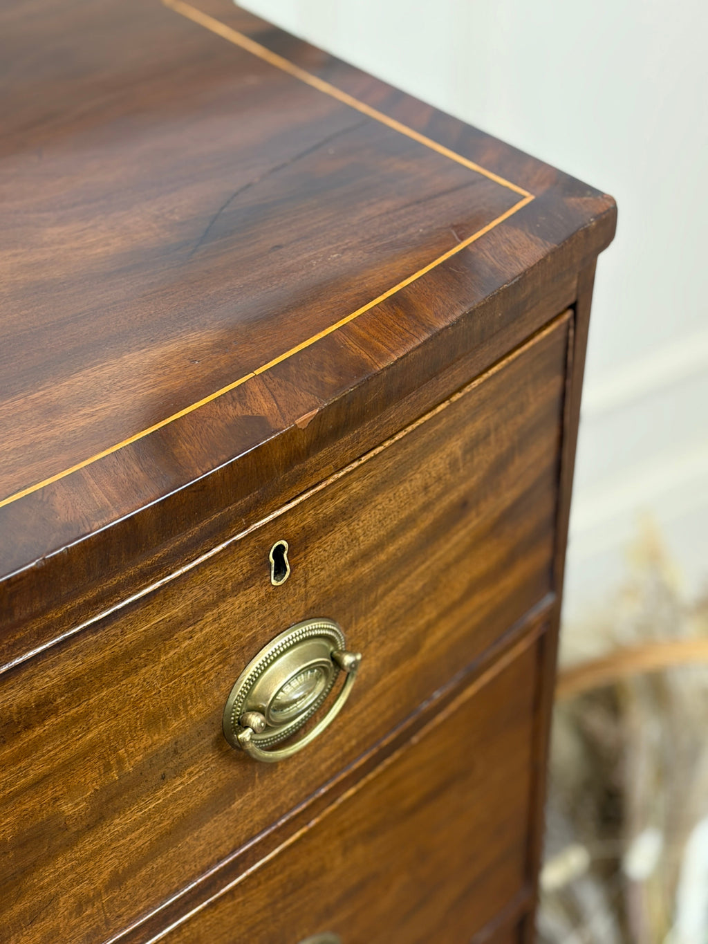 Wooden dresser with brass handle and keyhole on a blurred background