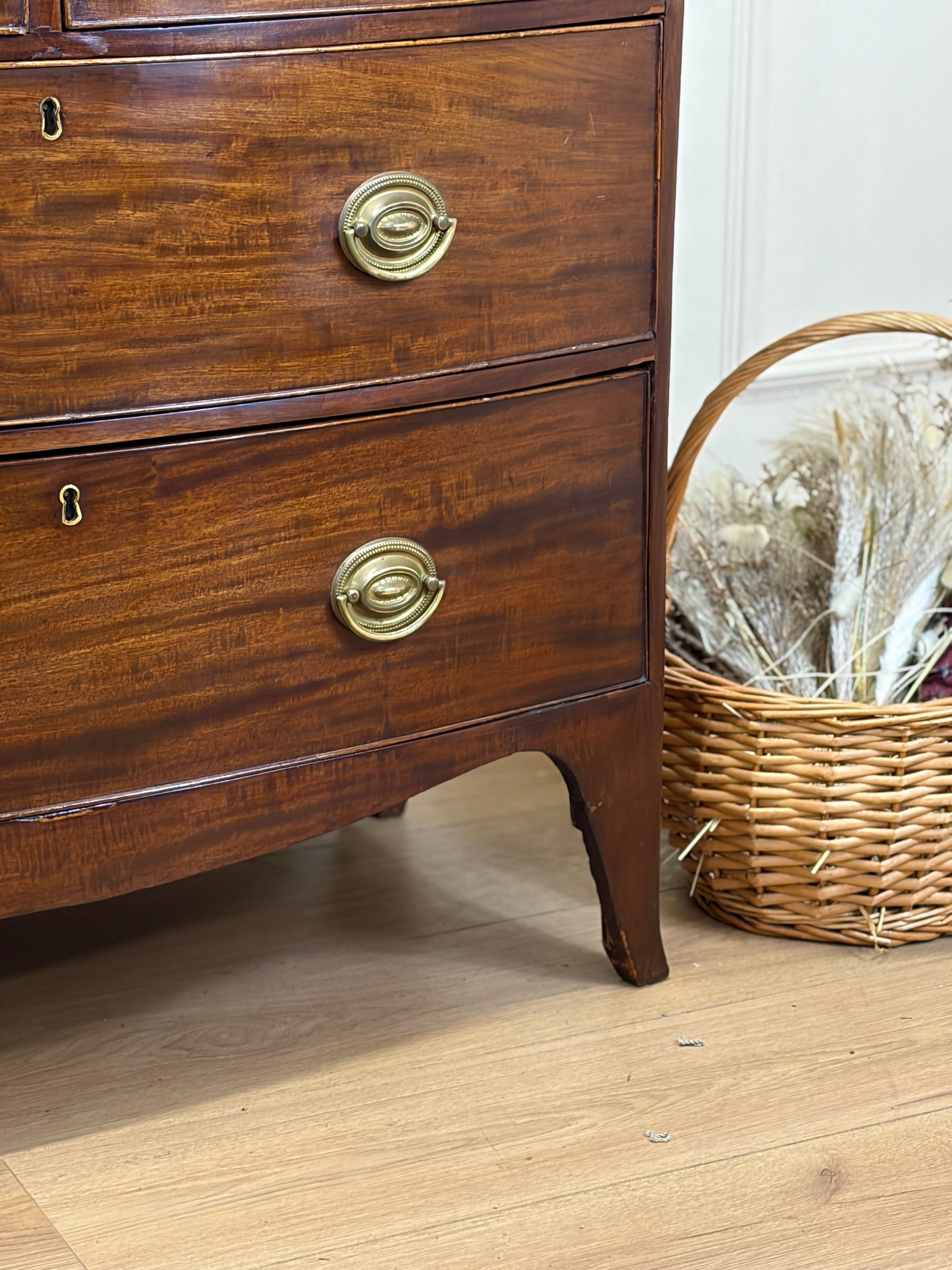 Wooden dresser with brass handles on a wooden floor next to a wicker basket.