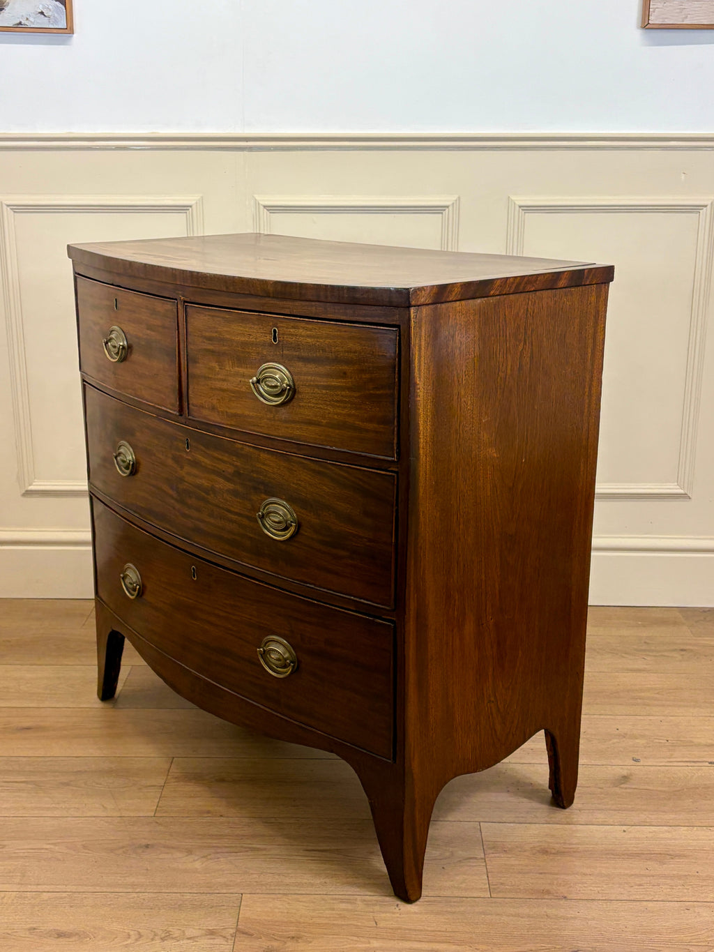 Wooden dresser with three drawers on a wooden floor against a white paneled wall.