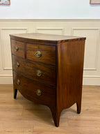 Wooden dresser with three drawers on a wooden floor against a white paneled wall.