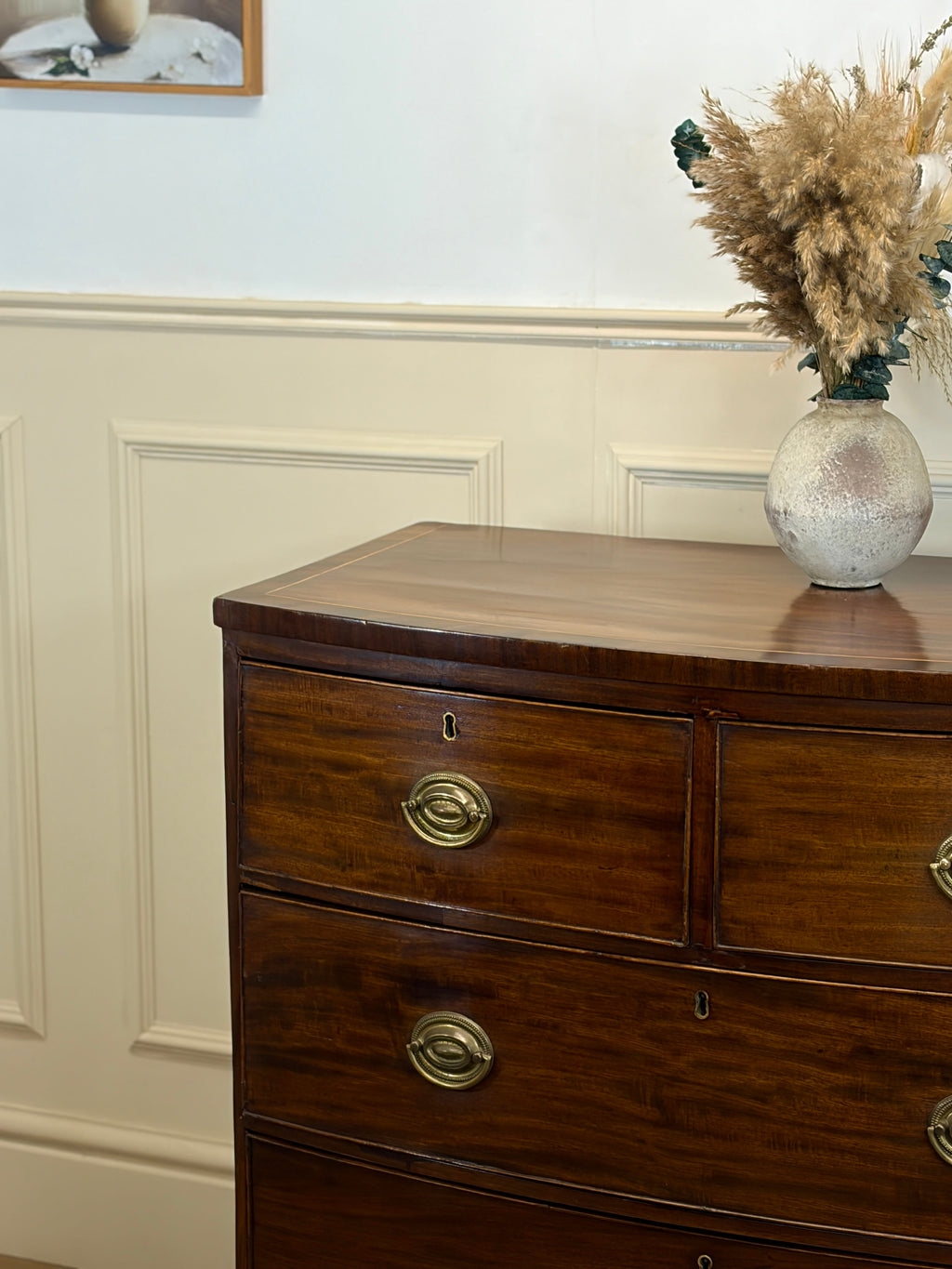 Wooden dresser with brass handles against a white wall