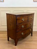 Wooden dresser with three drawers on a wooden floor against a white paneled wall.
