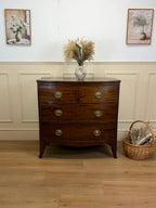 Wooden dresser with decorative items in a room with framed pictures on the wall.