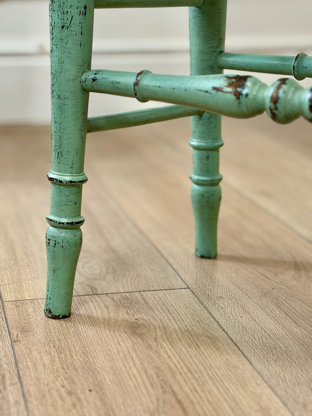 Green metal chair leg on a wooden floor