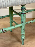 Close-up of a chair with a worn green metal frame on a wooden floor.