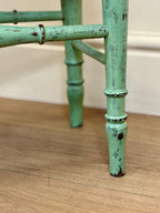 Close-up of a green bamboo-style chair leg on a wooden floor.