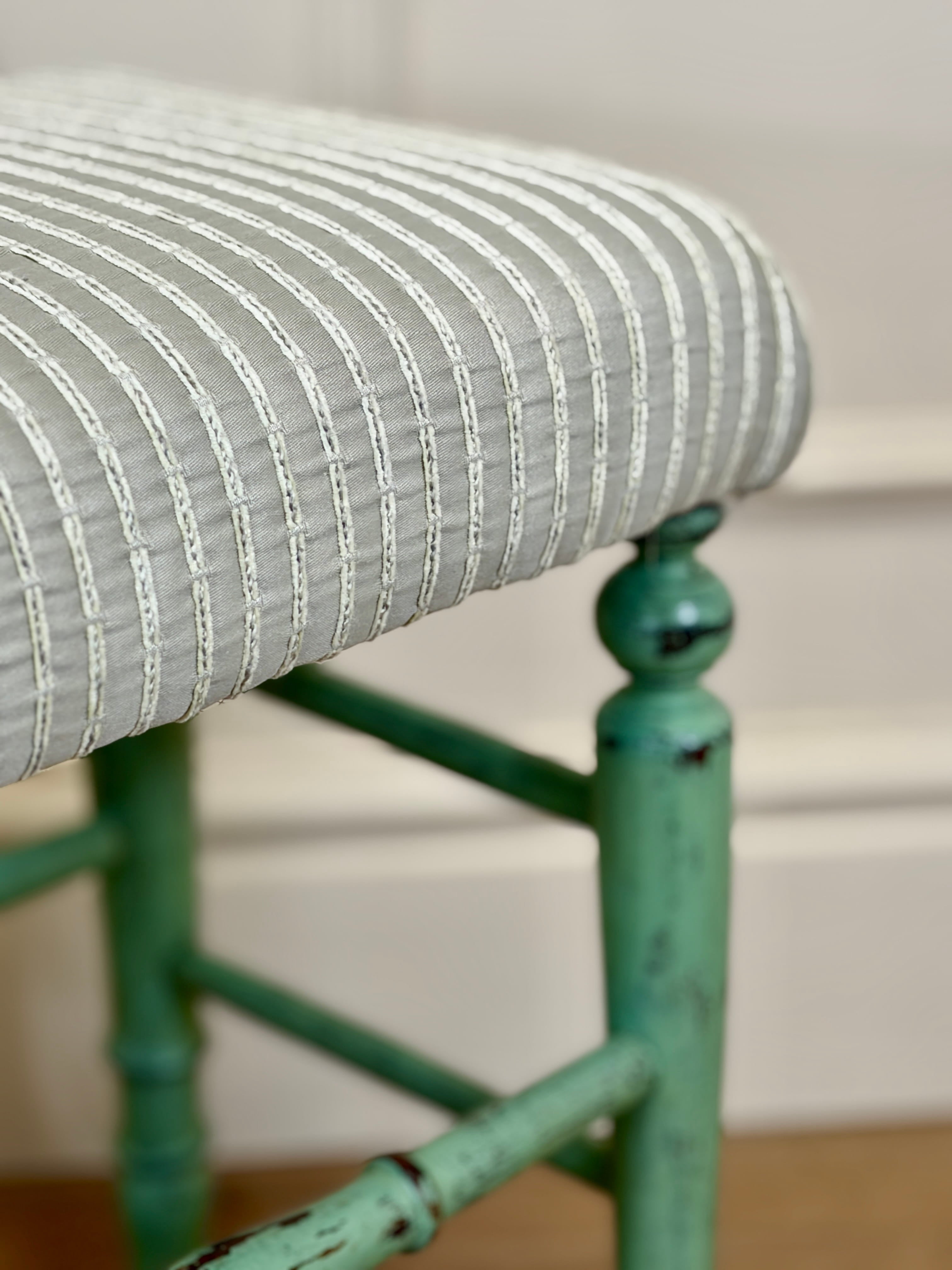Close-up of a green chair with striped cushion on a neutral background