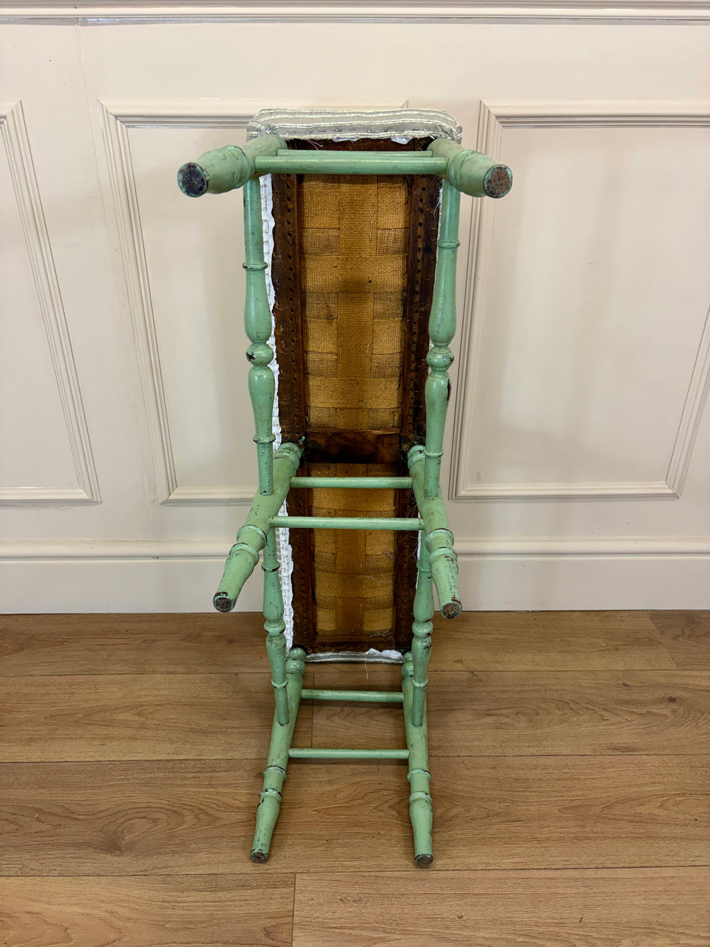 Green bamboo-style ladder against a white paneled wall.