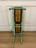 Green bamboo-style ladder against a white paneled wall.