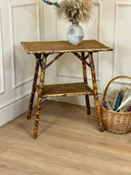 Small bamboo side table with a vase and basket on a wooden floor.