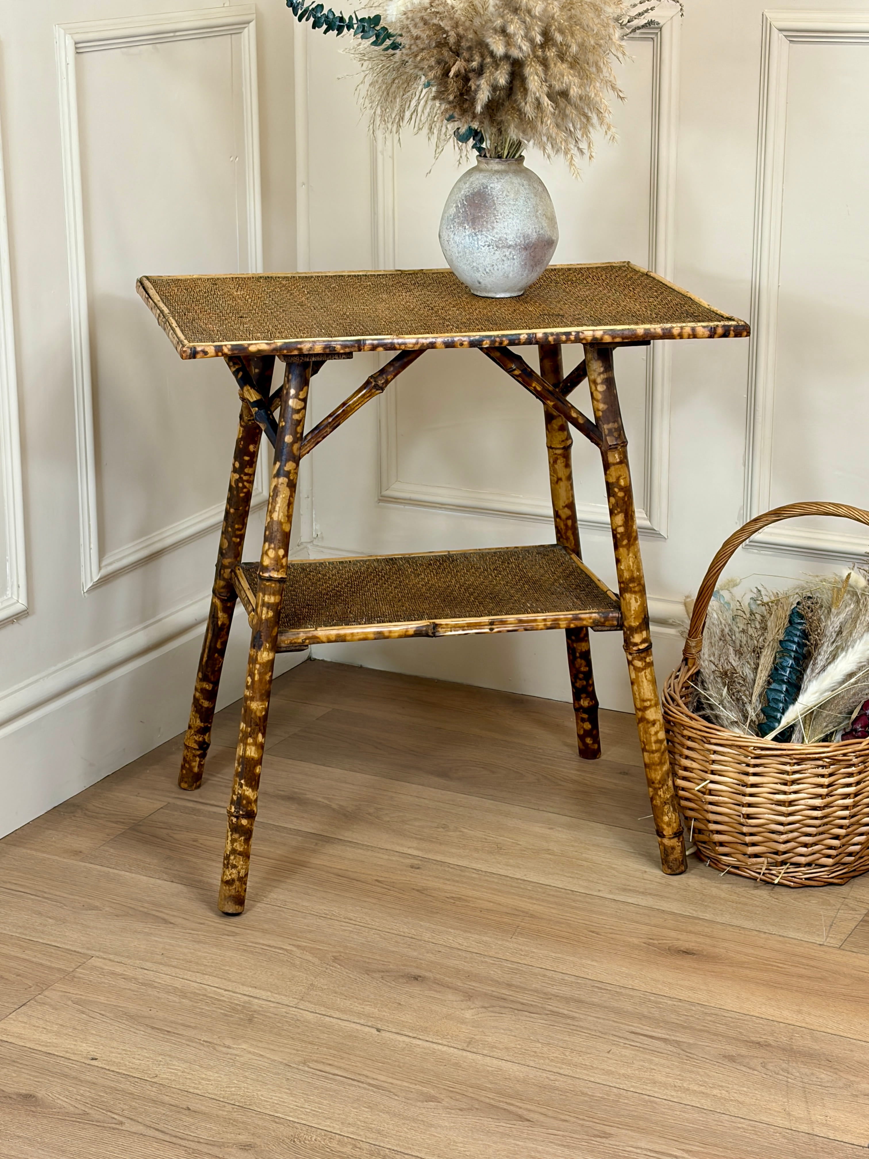 Small bamboo side table with a vase and basket on a wooden floor.