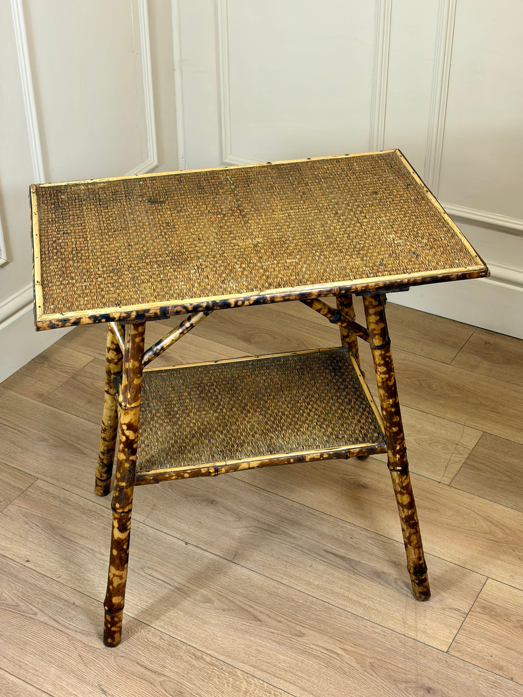 Tortoiseshell side table with wicker design on a wooden floor.