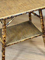 Rattan side table with two shelves on a wooden floor.